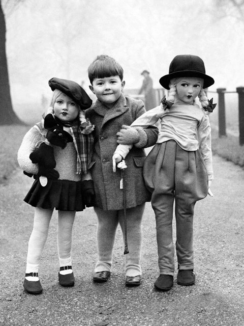 14. A young boy with two life size dolls in Hyde Park, London.